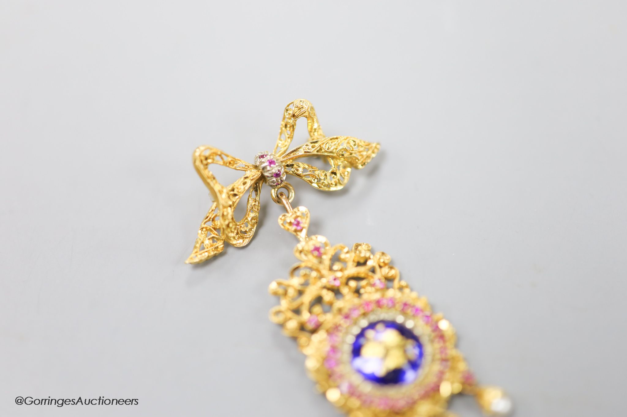 An early 1960's 18ct gold, ruby seed pearl and enamel set drop pendant, suspended from a ribbon bow brooch, import marks for Birmingham, 1960, overall 65mm